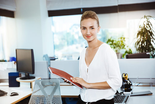 Businessfrau mit Ringbuch vor Schreibtisch